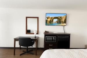 a bedroom with a desk and a television and a mirror at Big Chief Motel in Battle Mountain