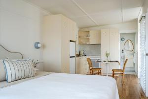 a bedroom with a white bed and a small kitchen at The Bunkie @ Ethel & Odes in Bundeena +24 photos