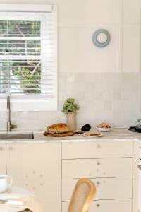 a white kitchen with a sink and a counter top at The Bunkie @ Ethel & Odes in Bundeena