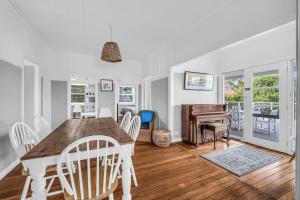 a dining room with a table and chairs and a piano at Murrah Street, 40 in Bermagui