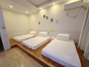 two beds in a hospital room with white sheets at The Cozy Nook in Zhangjiajie