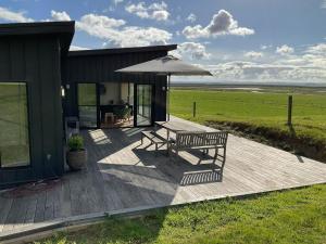 a wooden deck with a bench and an umbrella at Ngurra in Evergreen