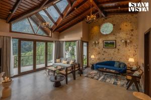 un salon avec de grandes fenêtres et un canapé bleu dans l'établissement StayVista at Avasa Stays with Views, Jacuzzi, Meals, à Nainital