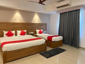 a bedroom with two beds with red pillows at Hotel Mangala Temple View in Guruvāyūr +26 photos