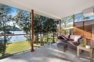 a living room with a couch and large windows at Lakeside - relaxed 3 BR waterfront retreat in Burrill Lake