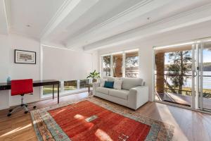 a living room with a couch and a desk at Lakeside - relaxed 3 BR waterfront retreat in Burrill Lake +21 photos