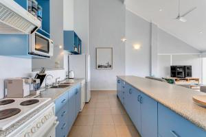 a kitchen with blue cabinets and a white refrigerator at 115 Seagull - Beachfront - Wi-Fi - No Linen Included in Hayborough