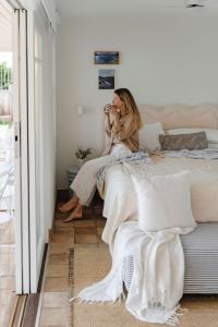 a woman sitting on a bed talking on a cell phone at Fogo @ Ethel & Ode’s in Bundeena