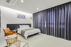 a hotel room with a bed and a chair at Hoteld Benikea in Osan