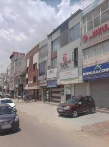 a city street with cars parked in front of buildings at hotel grand in Zirakpur +1 photo