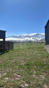 een hek in een veld met besneeuwde bergen op de achtergrond bij Shahdag Nature House in Qusar