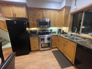 a kitchen with wooden cabinets and a black refrigerator at Mountainside Family Chalet in Yosemite West +15 photos