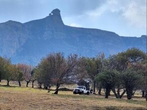 a truck parked in a field in front of a mountain at Mount Everest Guest Farm in Harrismith +6 photos