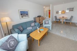 宾茨Villa A Cappella Binz - Wohnung C5的客厅里有一张蓝色的沙发和一张桌子 更多9张照片