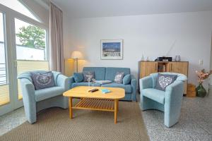 宾茨Villa A Cappella Binz - Wohnung C5的客厅配有2把蓝色椅子和咖啡桌