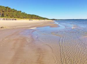 a sandy beach with a group of people in the water at Strandresort Prora - Wohnung 213 in Binz