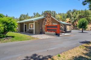 a small log cabin with a stone chimney on a road at Modern Cabin Bungalow in Mariposa +33 photos