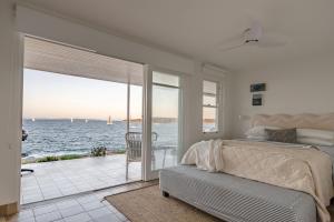 a bedroom with a bed and a view of the ocean at Fogo @ Ethel & Ode’s in Bundeena
