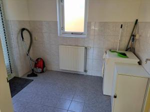 eine kleine Küche mit einer Waschmaschine und einem Fenster in der Unterkunft Comfortabel landhuis voor rust en ontspanning in Schoonloo + 11 Fotos