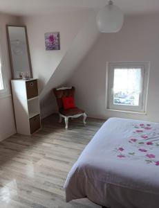 een slaapkamer met een bed, een stoel en een raam bij Petite maison Quartier Ste Croix in Josselin