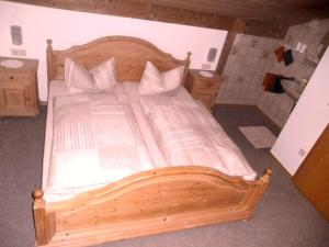 a bedroom with a wooden bed with white sheets and pillows at Dachgeschosswohnung Mit Toller Aussicht Vom Balkon in Bayersoien