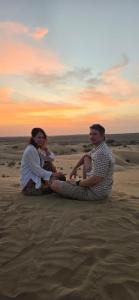 a man and a woman sitting in the sand at Relax Inn Jaisalmer in Jaisalmer