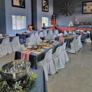 a banquet hall with tables and white chairs and tablesearcher at The Venue and Guestrooms ON SITE in Potchefstroom