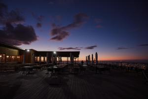 a deck with tables and chairs and a sunset at Le Mont in Almaty