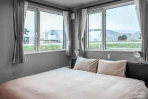 a bedroom with a white bed with three windows at Orvia Yig Villa in Furano +173 photos