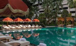 a swimming pool with chairs and umbrellas in a hotel at Anantara Siam Bangkok Hotel in Bangkok