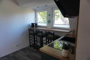 a kitchen with a counter with chairs and a window at Gemütliche Wohnung mit großer Dachterrasse in Röhrsen