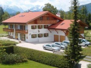 a large building with cars parked in a parking lot at Gästehaus Bernhard in Krün