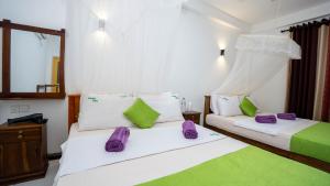Un dormitorio con dos camas con almohadas moradas y verdes. en Woodsy Villa, en Sigiriya