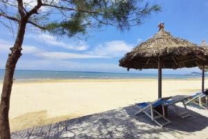 a beach with two chairs and a straw umbrella at Ruby Star Hotel Apartment in Vung Tau