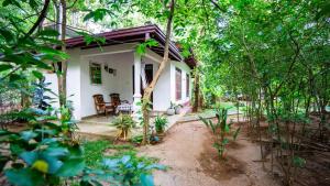 una pequeña casa blanca en medio de los árboles en Woodsy Villa, en Sigiriya