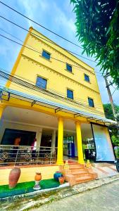 a yellow house with a woman sitting on a balcony at Cozy Bay Rawai in Phuket Town