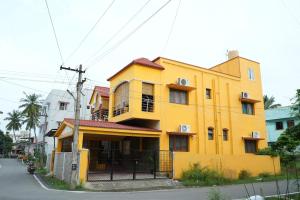 un edificio amarillo al costado de una calle en Deepam Haven Inn, en Gūduvāncheri