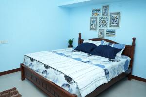 Un dormitorio con una cama con una pared azul. en Deepam Haven Inn, en Gūduvāncheri