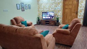 Una sala de estar con dos sofás y un televisor. en Deepam Haven Inn, en Gūduvāncheri