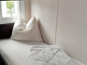ein Bett mit zwei Kissen neben einem Fenster in der Unterkunft Luxus Chalet im schönen Recratiepark De Veerstal in Rheden