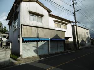 a white building on a street next to a road at 九州 福岡 貸切 プライベートハウス 