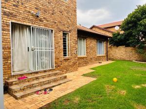 ein Backsteinhaus mit einer Tür und einem Rasen mit Schuhen in der Unterkunft Pelistay in Sundowner in Boskruin