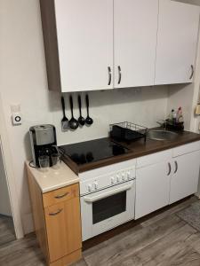 a kitchen with white cabinets and a stove top oven at FeWo Papenburg im OG - Nähe City in Papenburg