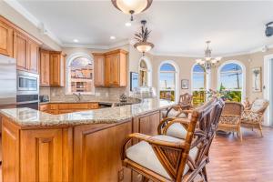 een keuken met houten kasten en een groot eiland met barkrukken bij Villa Vista Mare - 675 in Siesta Key