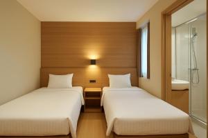 two beds in a hotel room with a bathroom at Busan Seomyeon Nestly Hotel in Busan +10 photos