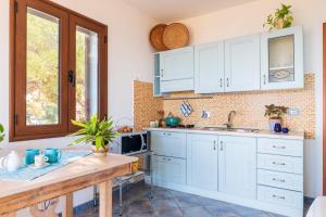 a kitchen with white cabinets and a sink at Mini Appartemento vista mozzafiato in Santa Maria Navarrese