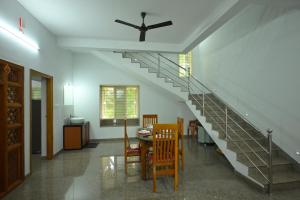 a staircase in a living room with a table and chairs at Prashanthi Nature View - Luxury 2Bhk Villa in Udupi