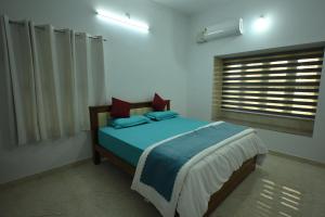 a bedroom with a bed with blue sheets and a window at Prashanthi Nature View - Luxury 2Bhk Villa in Udupi