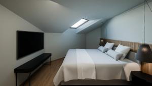 a bedroom with a white bed and a flat screen tv at Hotel Rosatsch in Pontresina