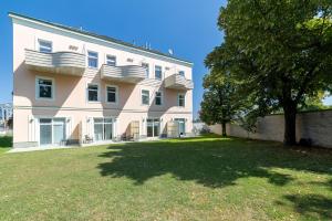 a large white building with a tree in front of it at Giardino Airport Apartment with garden in Schwechat